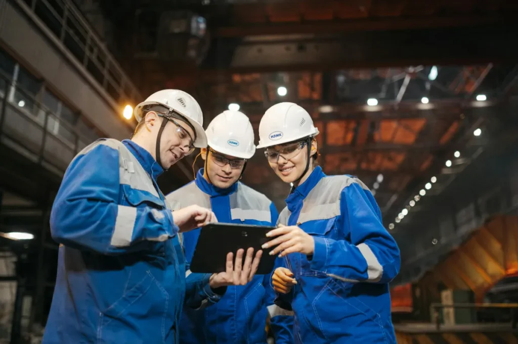 Sekelompok engineer mendiskusikan proyek di tablet dalam lingkungan pabrik industri
